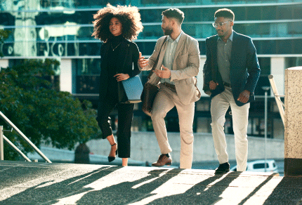 Group of diverse young professionals walking together outside a modern building.