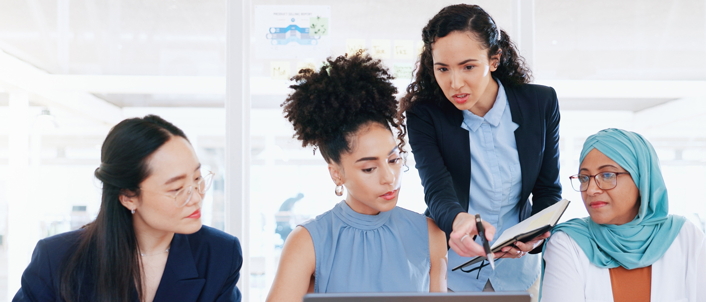 "Diverse group of professional women collaborating in a modern office, reviewing a document together.