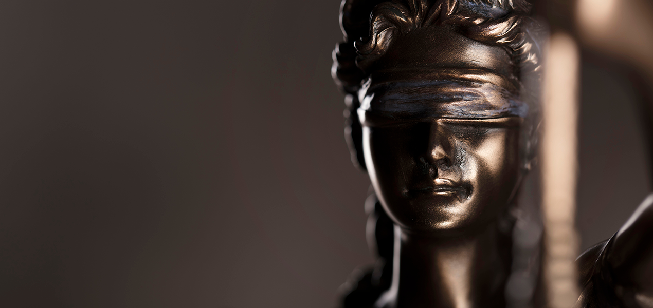 Close-up of a bronze Lady Justice statue, blindfolded and holding scales, symbolizing fairness, law, and impartiality.