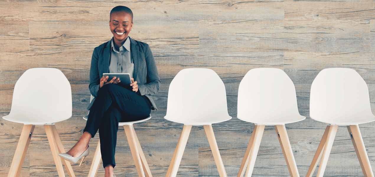 Job candidate sitting alone in a modern waiting room before an interview, surrounded by empty white chairs in a professional office setting.