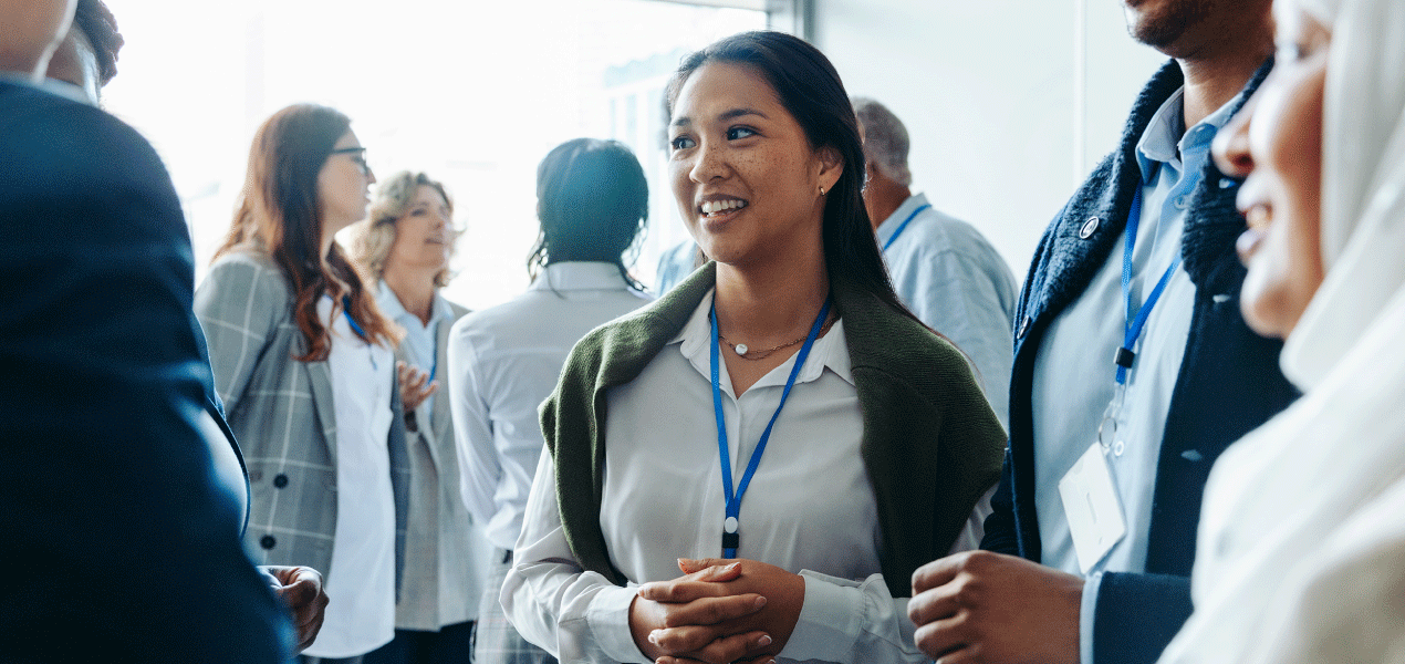 Audience seated in rows of a conference auditorium, watching a presentation under colorful stage lighting during a professional event.