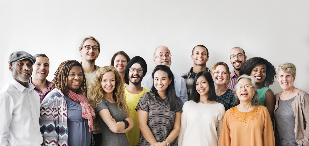 Diverse team standing and smiling against a white wall.