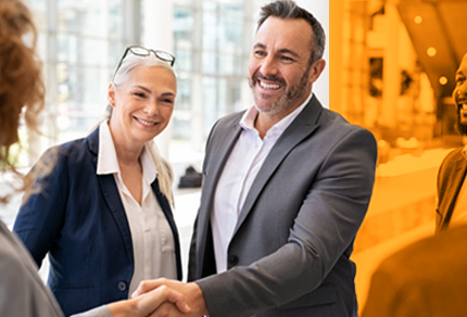 Smiling business professionals shaking hands in a modern office setting, with a warm and welcoming atmosphere.