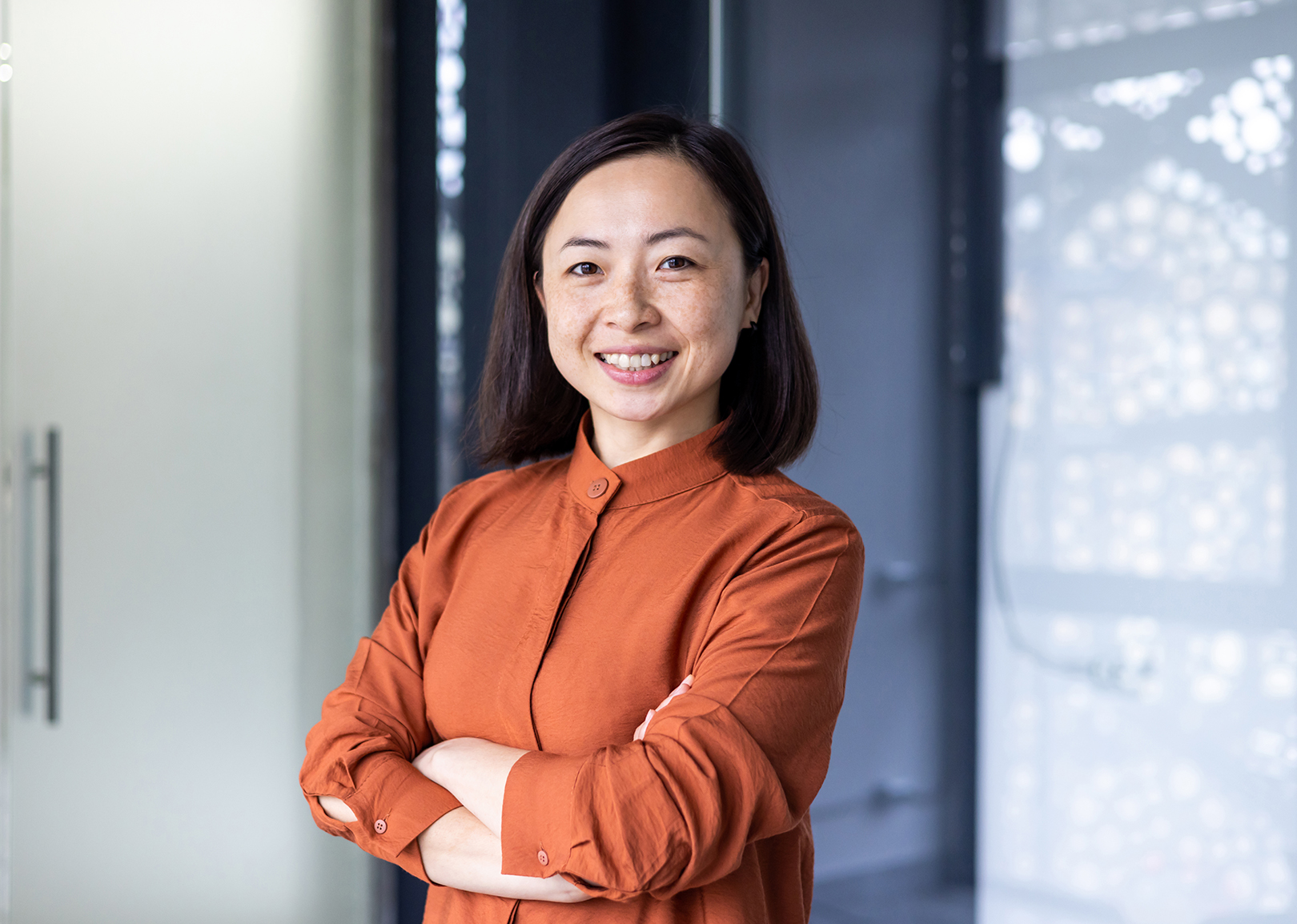 professional woman standing with arms crossed in front of doorway