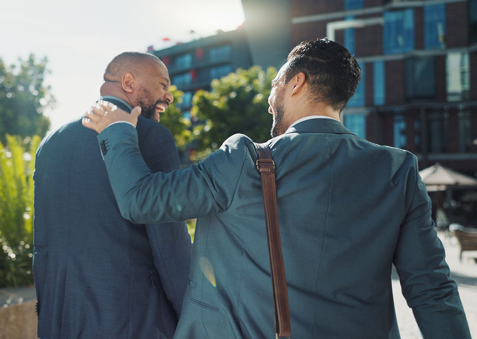 Two men walking outdoors, one putting his and on the others back