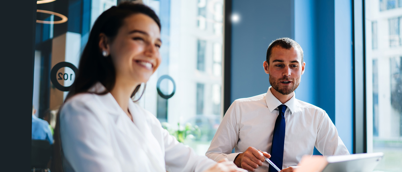 Two professionals in a modern office, engaged in a discussion with a bright and collaborative atmosphere.