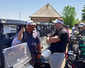 participants in Golf Day gather around the golf carts