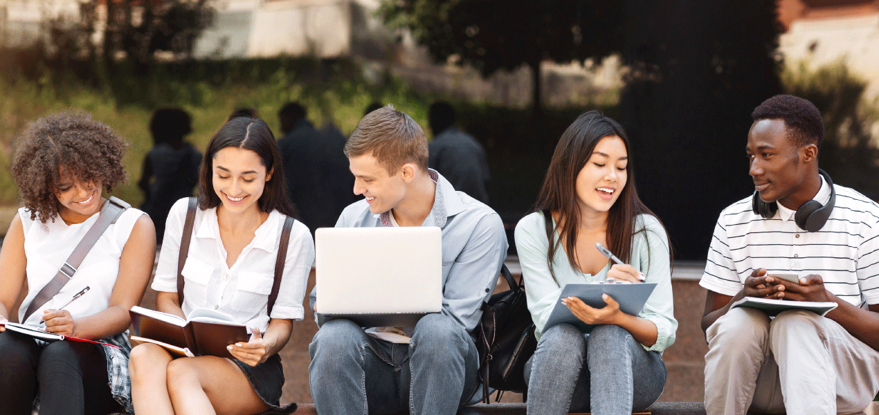 Diverse group of university students sitting together with laptops and books.