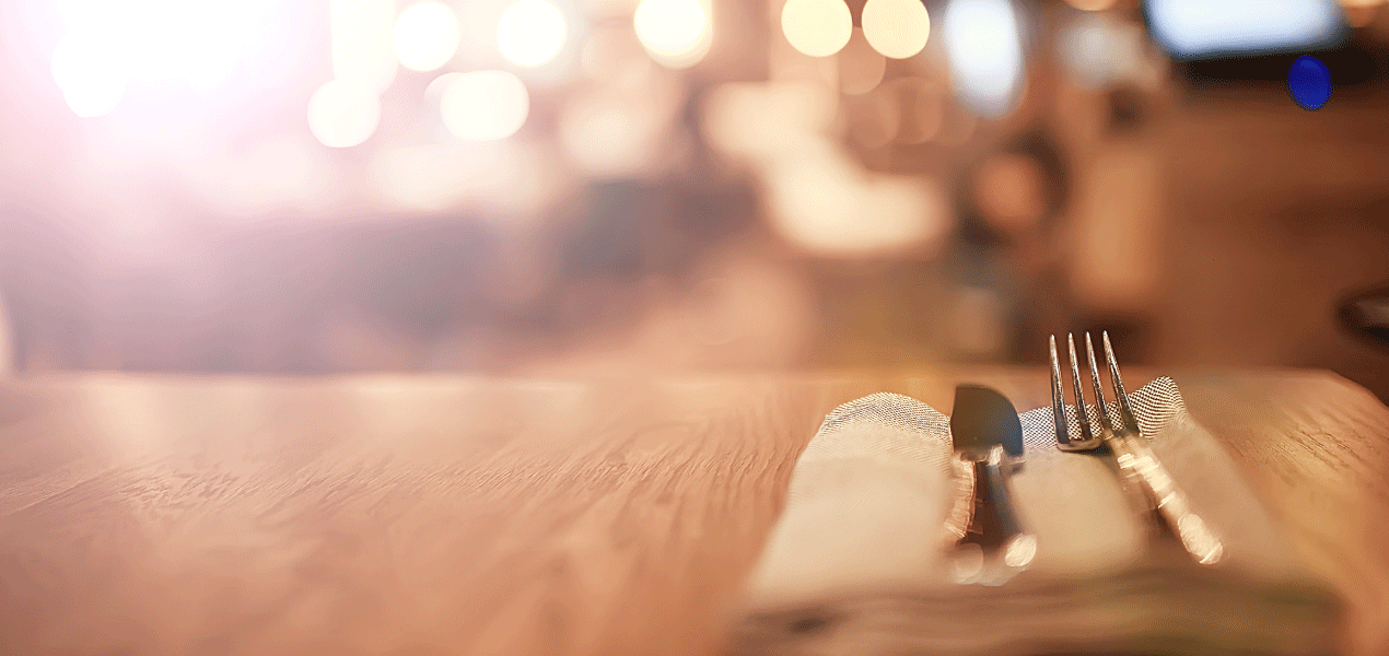 Table set with cutlery inside a warmly lit bar