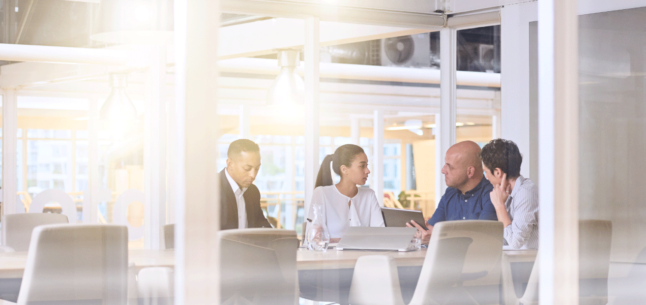 Professionals meeting in a bright, glass-walled conference room.