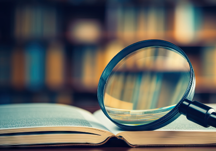 Magnifying glass resting on an open book in a library.
