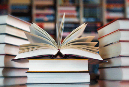 Open book surrounded by stacks of books in a library