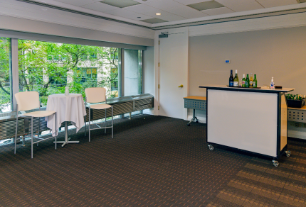 Open concept room with bar set up and chairs and table in front of window.